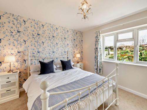 a bedroom with a white bed with blue floral wallpaper at 1 Bed in Great Torrington 89636 in Great Torrington