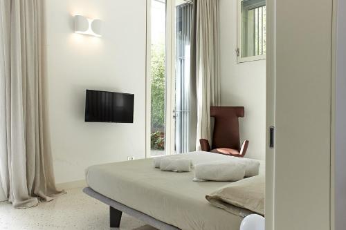 1 dormitorio con 1 cama, TV y silla en Il Giardino Segreto, en Sacile