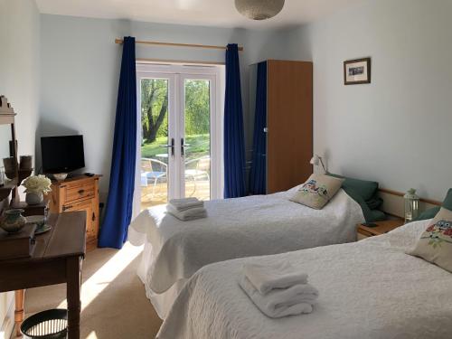 a bedroom with two beds and a sliding glass door at Offa's Dyke Lodge B&B in Gladestry