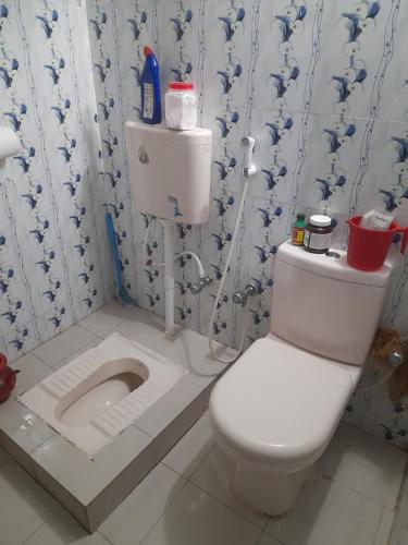 a bathroom with a white toilet with a sink at Isolated guest house in Sunāmganj