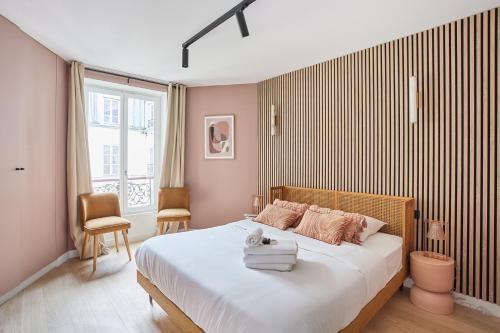 - une chambre avec un grand lit aux murs roses dans l'établissement Residence beaubourg by Studio prestige, à Paris