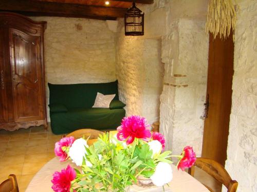 Masquières的住宿－Las Gonies - Clévacances 2 Clés，一张带鲜花的桌子和一张绿色沙发