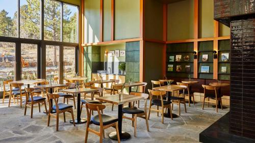 a restaurant with wooden tables and chairs and windows at Trailhead Lodge in Estes Park