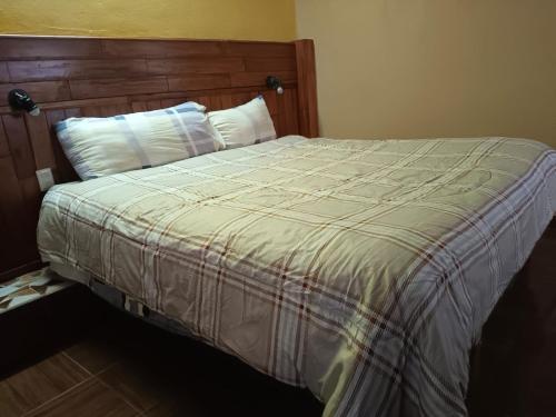 a bedroom with a bed with a wooden headboard at Casa Granada Jilotepec in Jilotepec