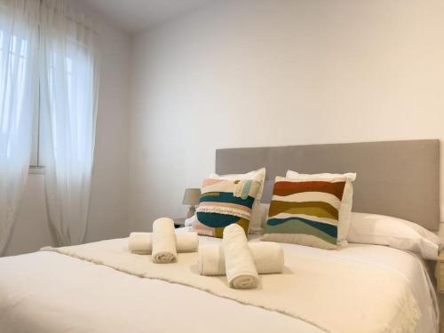 ein weißes Bett mit Kissen darüber in der Unterkunft Apartamentos Gredos 001 in Jaraiz de la Vera