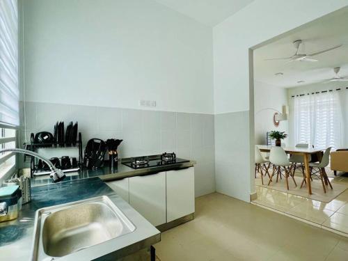 a white kitchen with a sink and a table at Cozy Scandi home @ Balok! in Kampung Saberang Balok