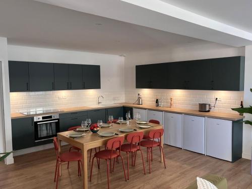 une cuisine avec une table en bois et des chaises rouges dans l'établissement La Casa Calot, à Angers