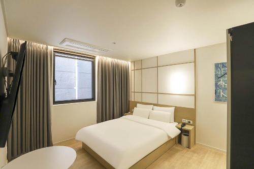 a bedroom with a white bed and a window at The Hyoosik Aank Hotel Daejeon Yooseong Hot Spring 1st Branch in Daejeon