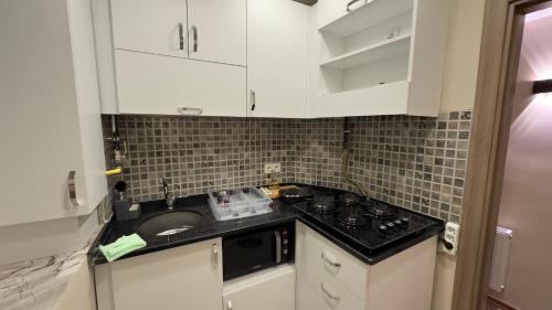eine Küche mit weißen Schränken und einem Waschbecken in der Unterkunft Golden Tulip Suite Apart in Istanbul