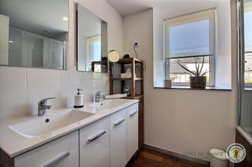 a bathroom with a sink and a mirror and a window at La maison de lannion in Lannion