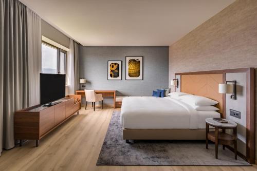 um quarto de hotel com uma cama e uma televisão de ecrã plano em Geneva Marriott Hotel em Genebra