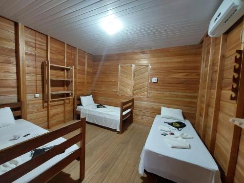 Habitación con 2 camas en una habitación con paredes de madera. en Amazon Seringal jungle Lodge en Careiro