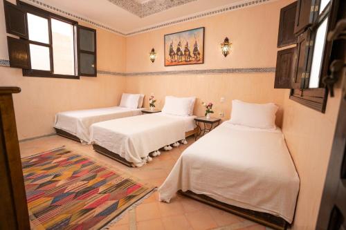 1 dormitorio con 2 camas y alfombra en Riad Atlas Toyours, en Marrakech