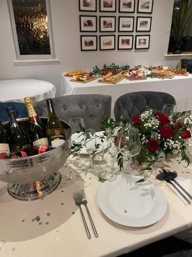 a table with a bowl of wine bottles and flowers at The Green Inn in Goole