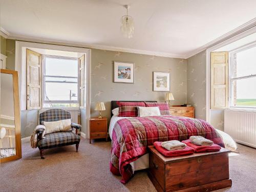 a bedroom with a bed and a chair and two windows at 3 Bed in Kinglassie FF224 in Kinglassie