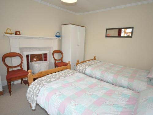 a bedroom with two beds and two chairs and a fireplace at 1 bed property in Lochinver The Highlands SU304 in Lochinver