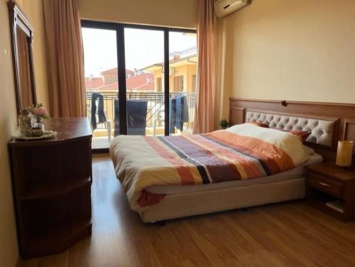a bedroom with a bed and a dresser and a window at Apartment Golden Sands and Black Sea, Varna in Golden Sands