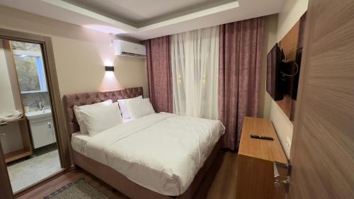 1 dormitorio con cama blanca y ventana en Golden Tulip Suite Apart, en Estambul