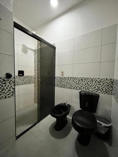 a bathroom with a black toilet and a shower at Apartamento cerca del Aeropuerto in Colonia Mariano Roque Alonso