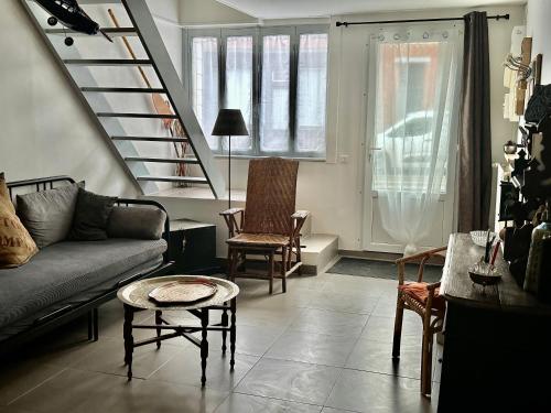 a living room with a couch and chairs and a staircase at Maison Pi Mouss' à 150m de la mer in Cayeux-sur-Mer