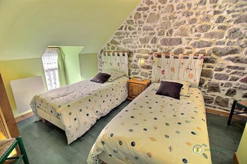 a bedroom with two beds and a stone wall at Tournesol in Saint-Gildas