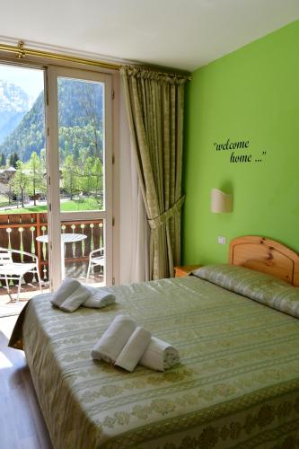1 dormitorio con 1 cama con pared verde en Hotel Saisera, en Valbruna