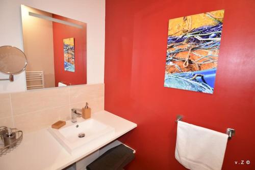 La salle de bains est pourvue d'un lavabo blanc et d'un mur rouge. dans l'établissement La villa des amiets, piscine chauffée et à 500 m de la plage, à Cléder
