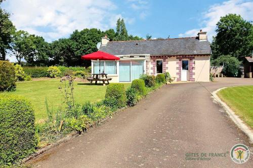 a small house with a red umbrella on a road at Des trois fleurs in Plouguenast Langast