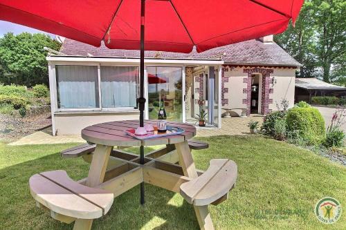 a picnic table with two chairs and a red umbrella at Des trois fleurs in Plouguenast Langast