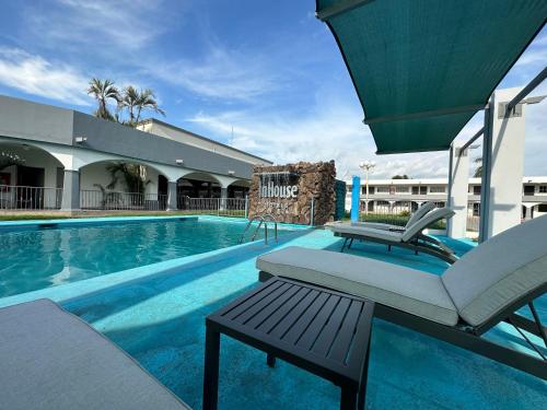 a pool with a bench and a chair next to a building at InHouse Hotel Obregón in Ciudad Obregón