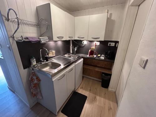 uma pequena cozinha com armários brancos e um lavatório em Charmant duplex 2 chambres/terrasse em Prades
