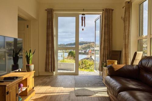 a living room with a couch and a large glass door at Luxury Waterfront House in Cobh