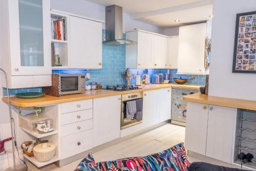 a kitchen with white cabinets and blue tiles at Cute & cosy 1 double bedroom garden flat in Brighton & Hove