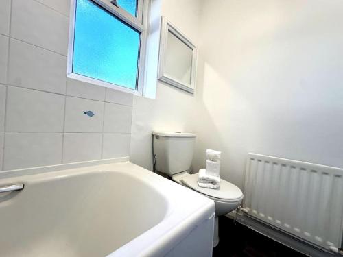 baño con bañera, aseo y ventana en Thorntree Place Blue Skies Stays, en Thornaby on Tees