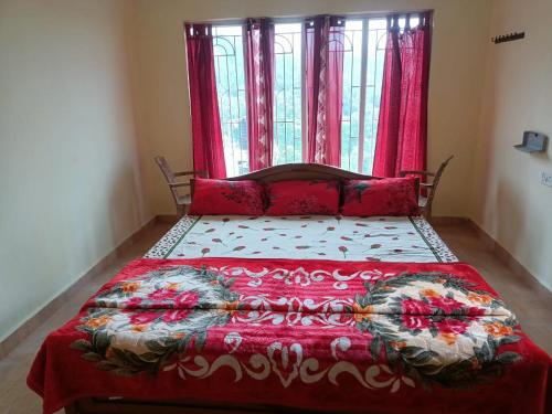a bedroom with a bed with a red blanket and a window at Wander Valley in Ooty