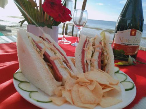 的住宿－Palaboy Skatecamp Beach Resort，夹在盘子里的三明治和薯条,配上一瓶葡萄酒