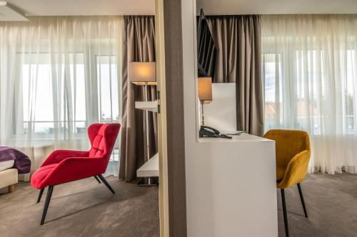 a hotel room with a red chair and a desk at Hotel Ózon & Luxury Villas in Mátraháza