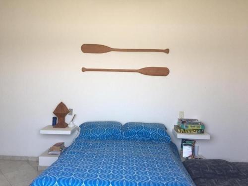 a bedroom with a blue bed and wooden paddles on the wall at Casa de Praia Com Piscina perto da praia in São João da Barra