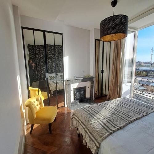 1 dormitorio con 1 cama, 1 silla y chimenea en Charming appartement with a view of the Saone, en Mâcon