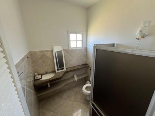 a bathroom with a toilet and a sink and a window at Casa de Praia Com Piscina perto da praia in São João da Barra