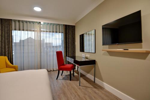 a hotel room with a bed and a desk and a television at The Capetonian - Halal in Cape Town