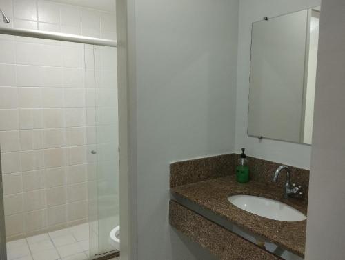 y baño con lavabo, espejo y ducha. en flats aconchegantes piscina e academia via park, en Campos dos Goytacazes