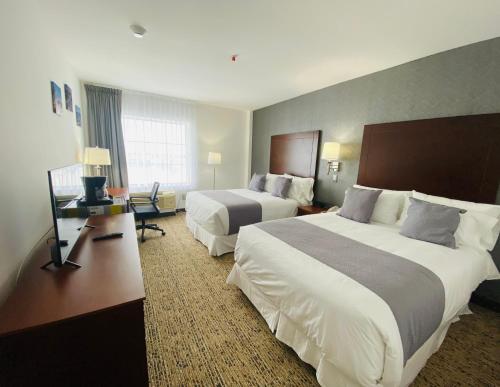 a hotel room with two beds and a desk at La Quinta by Wyndham Reynosa in Reynosa