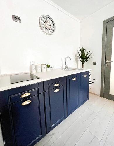 a kitchen with blue cabinets and a clock on the wall at Luxor - Jacuzzi&Cozy Apartments in Sibiu