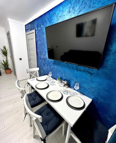 a white table with chairs and a tv on a blue wall at Luxor - Jacuzzi&Cozy Apartments in Sibiu