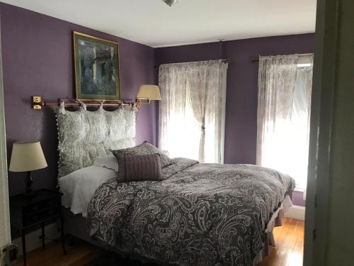 a purple bedroom with a bed and two windows at The Monadnock Inn in Jaffrey