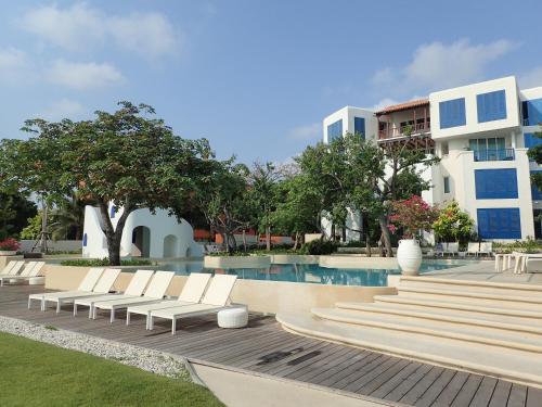 una piscina con tumbonas blancas junto a un edificio en Chelona Hua Hin, en Khao Tao