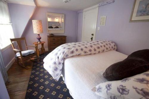 a bedroom with two beds and a lamp and a chair at The Monadnock Inn in Jaffrey