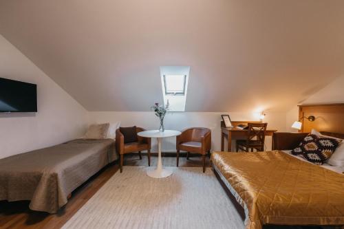 a hotel room with two beds and a table and a couch at CATHEDRAL Old Town Suites in Vilnius