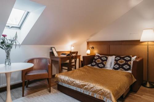 a bedroom with a bed and a desk and a table at CATHEDRAL Old Town Suites in Vilnius